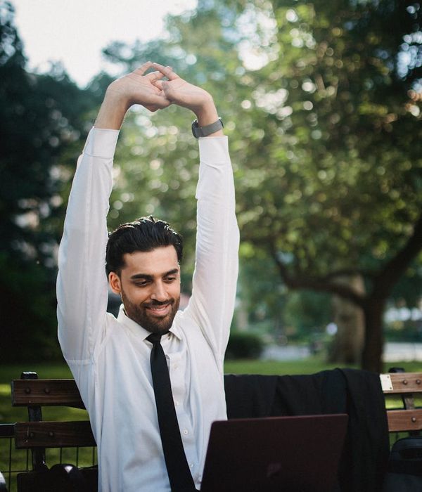 Person smiling and stretching outdoors in a park at sunrise.
